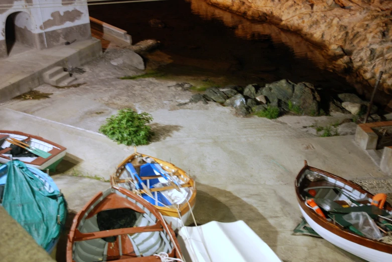 several small boats in an old building near other vessels