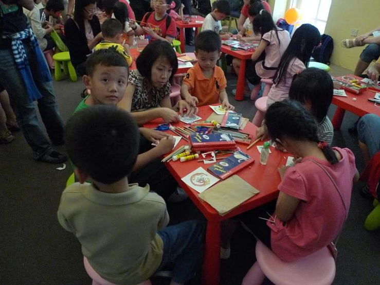 a number of children at tables with one person sitting