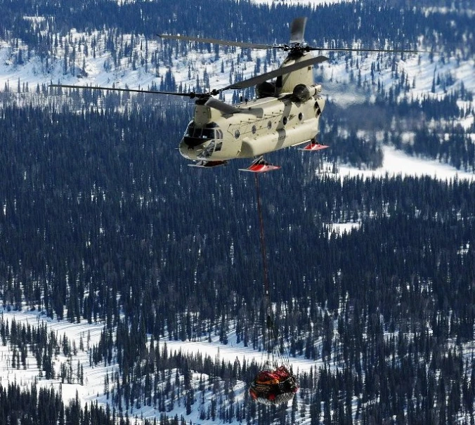 a helicopter lowers a tow rope over a forest
