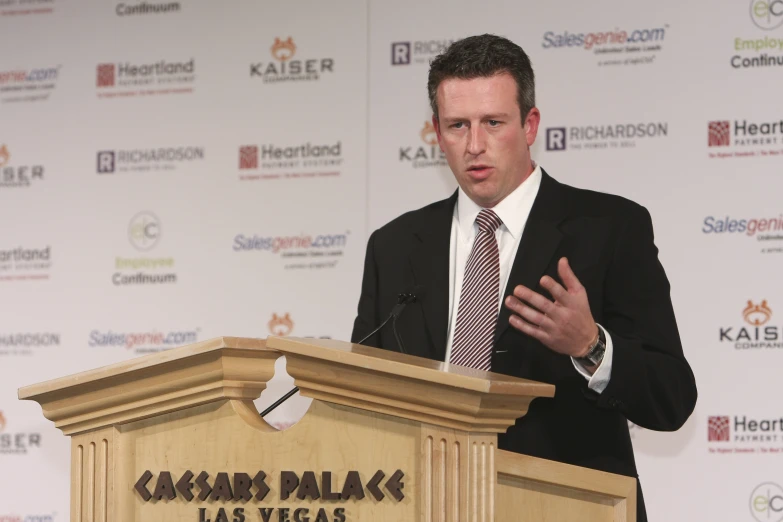 a man in suit speaking at a podium