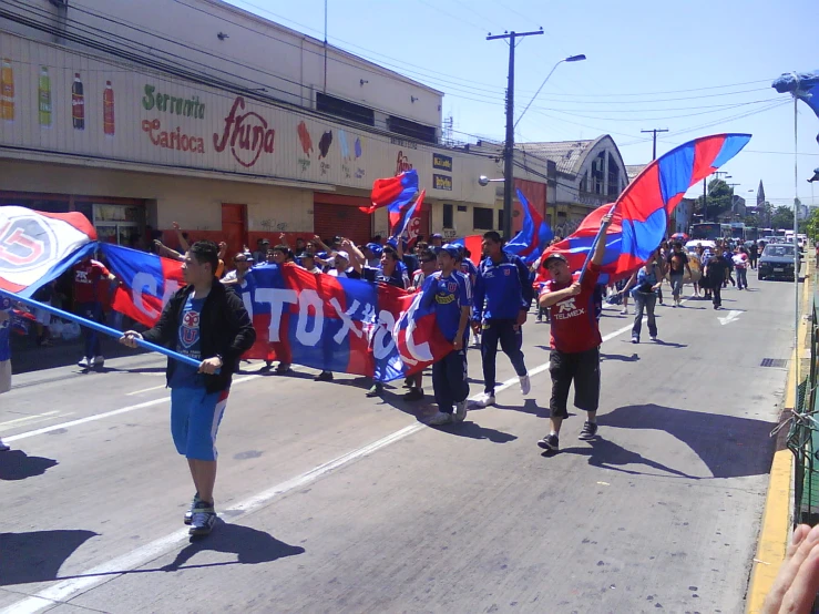 some people marching down the street with red and blue flags