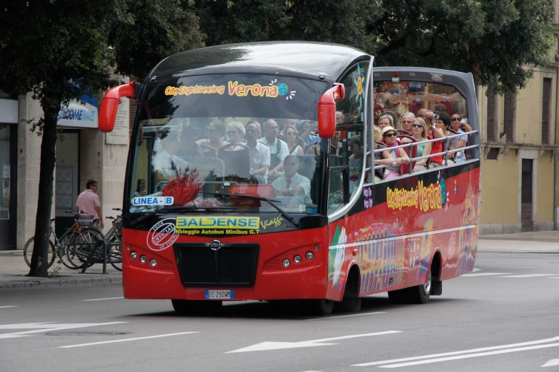 red bus with lots of people traveling down the street