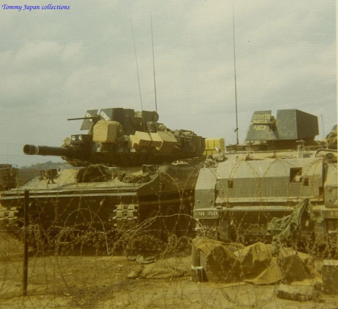 a couple of tanks in a field near a fence