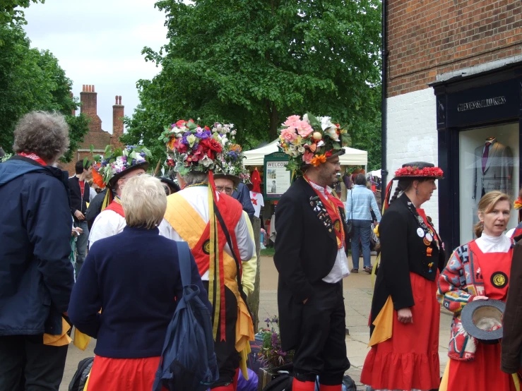 a group of men and women in dresses are walking in the street