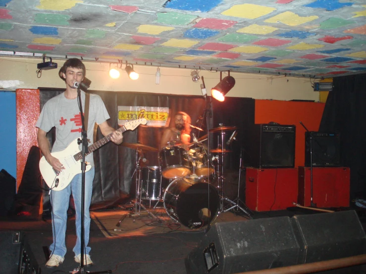 a man standing next to a microphone with an electric guitar