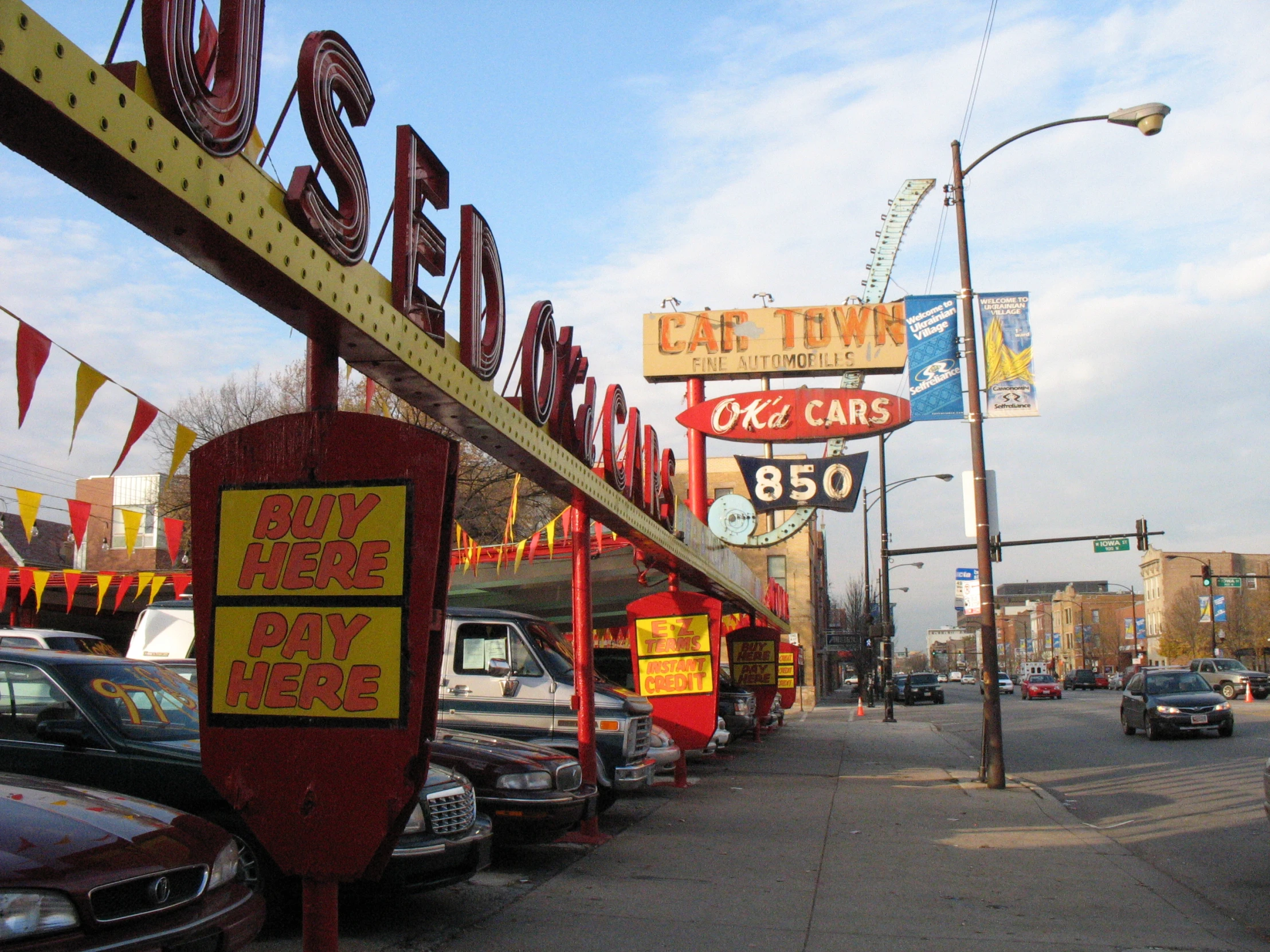 neon signs advertise businesses and cars parked