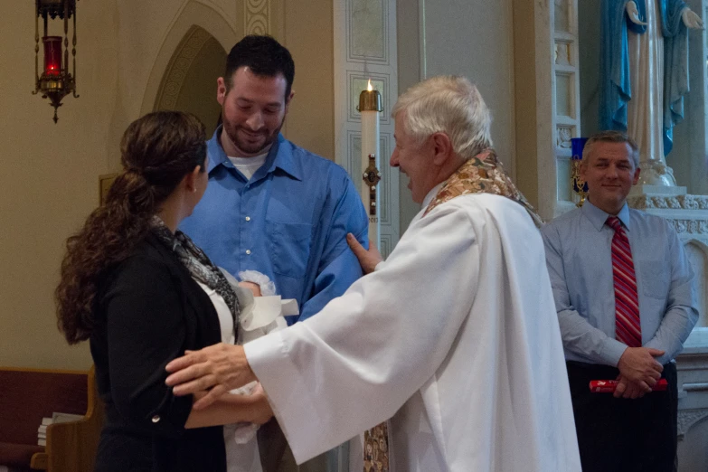 two priest handshaking in church with a woman