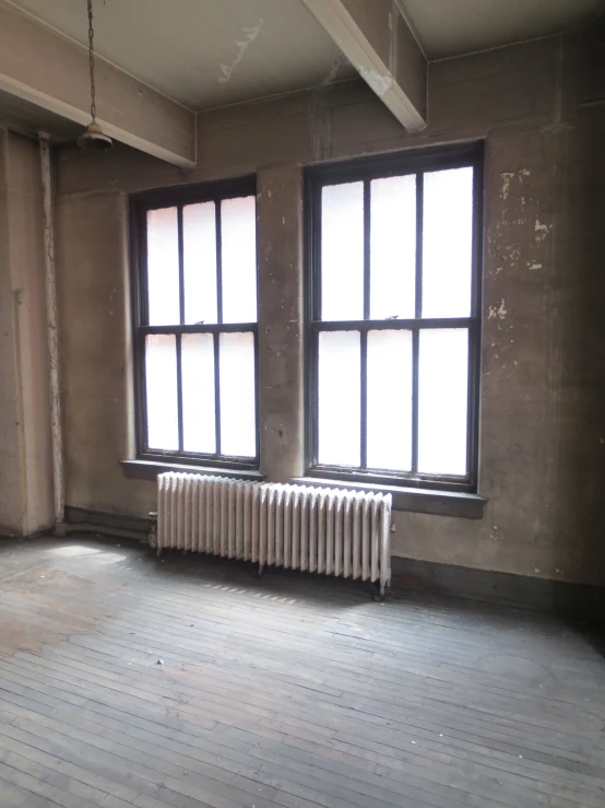 a large room with windows, wooden floor and radiator