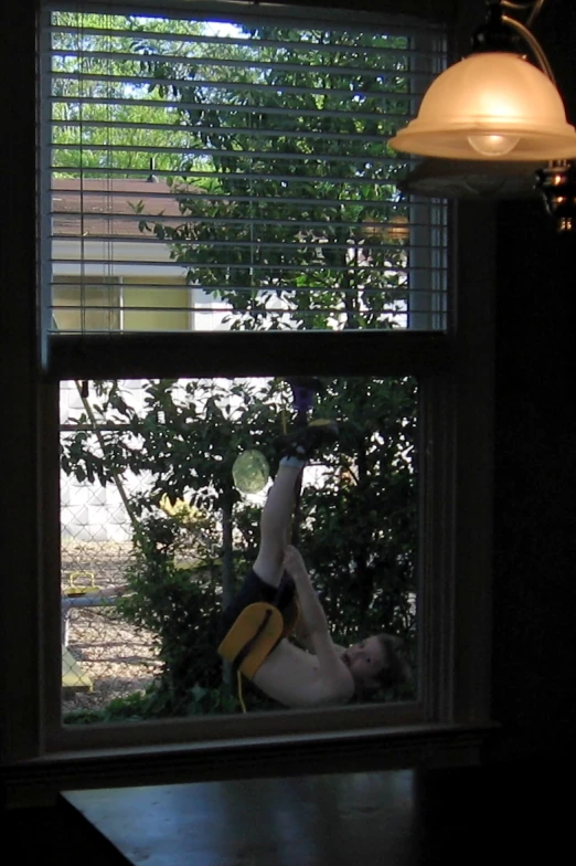 a window sill with blinds and a shirt hanging from the side