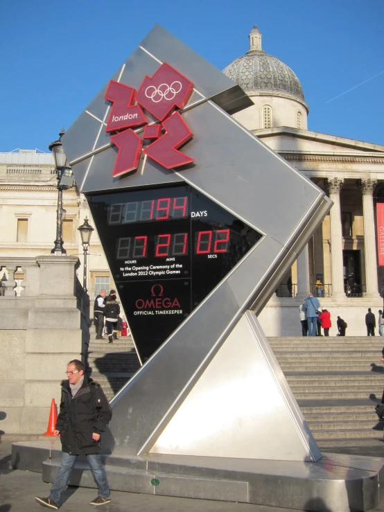 a man walking by a large digital clock