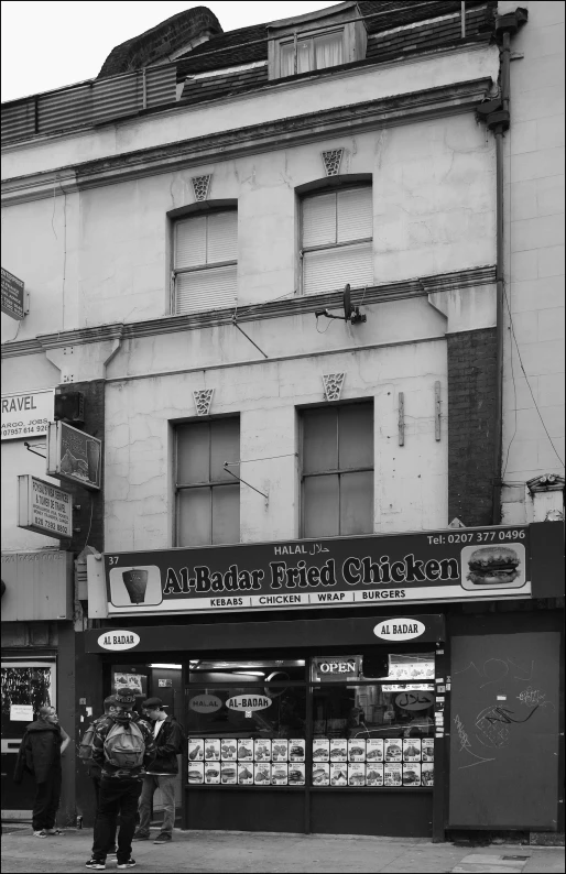 a black and white po shows two people walking through an alley near a store