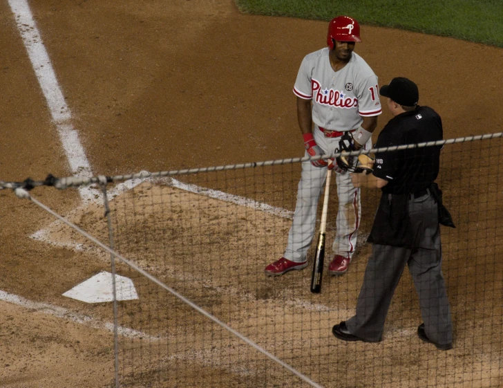 a baseball player in uniform talking to someone on the field