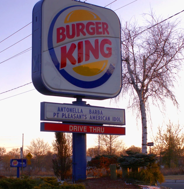 a burger king sign and road signage in front of trees