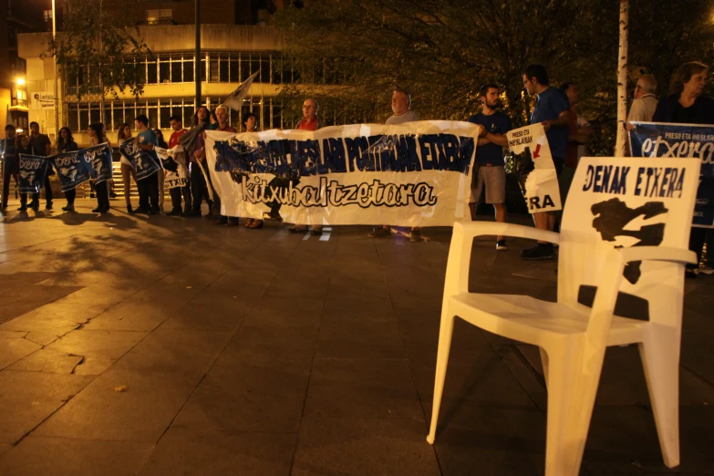 a row of people holding protest signs at night