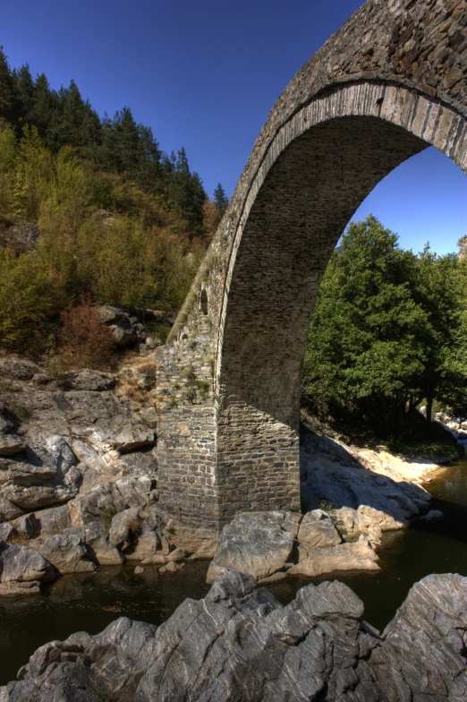 an arch in the side of a stone bridge over water