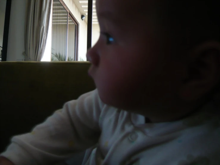 a little baby sitting in a chair next to a window