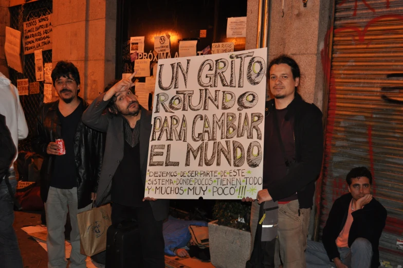 the men are holding a sign in spanish