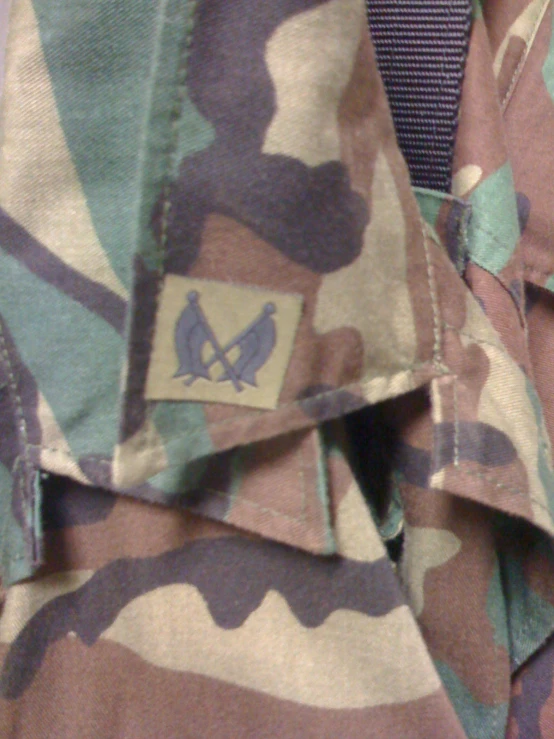 the camouflage jacket has a bird emblem and is purple, green, blue, white