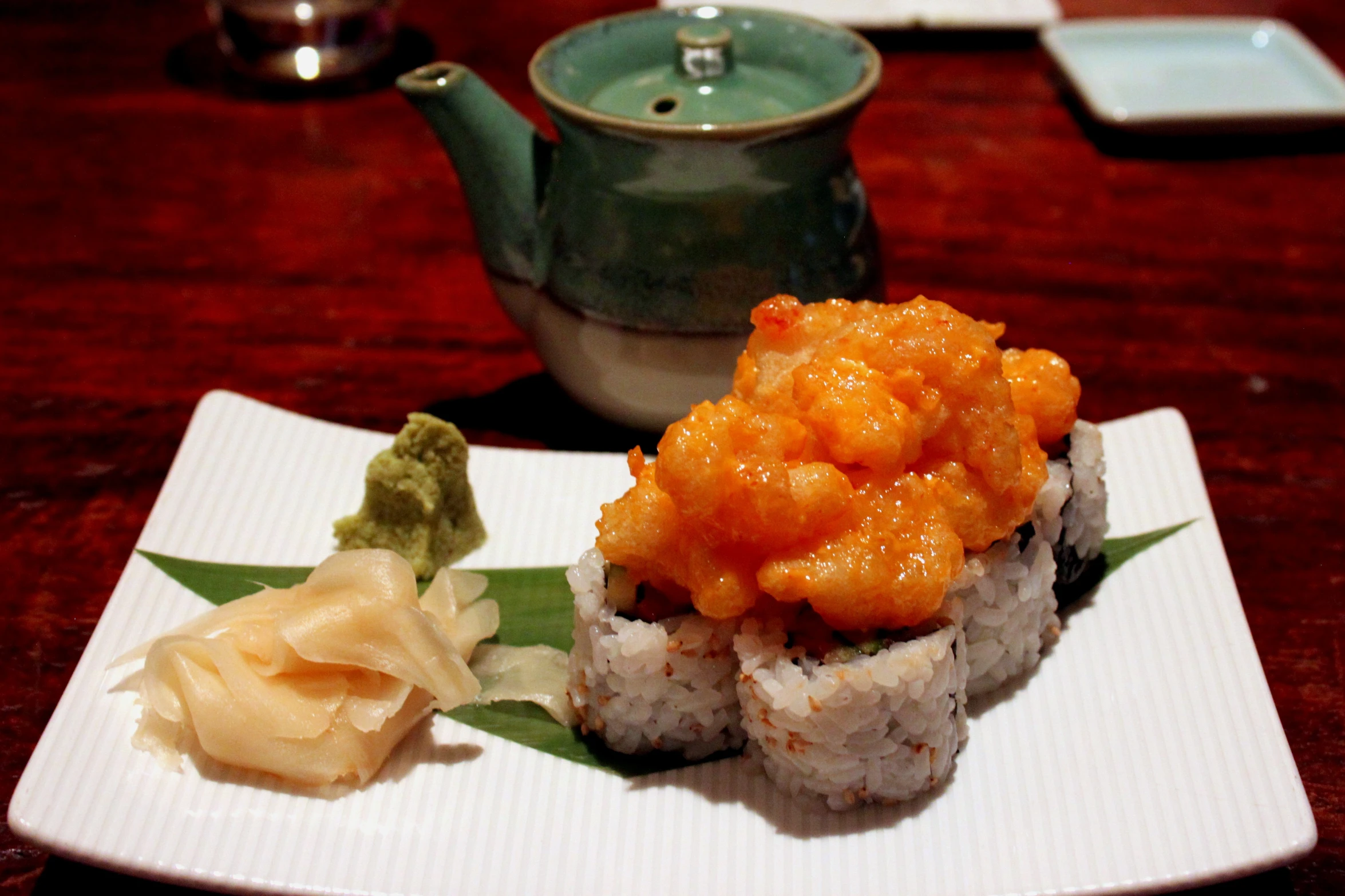 a plate full of sushi and a tea pot with some garnish