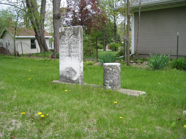two stone headstones sitting in a garden