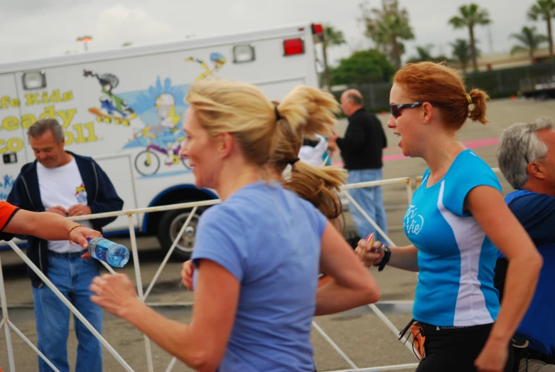 several people walking around with a medical service vehicle in the background