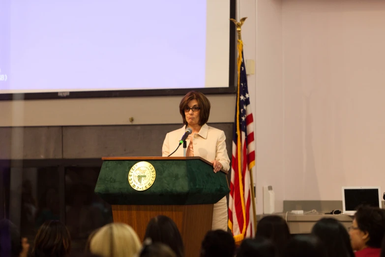 a woman at a podium with an american flag and a microphone