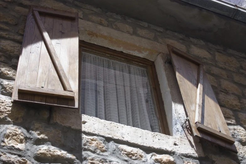 two old windows with shutters open on top of a stone wall