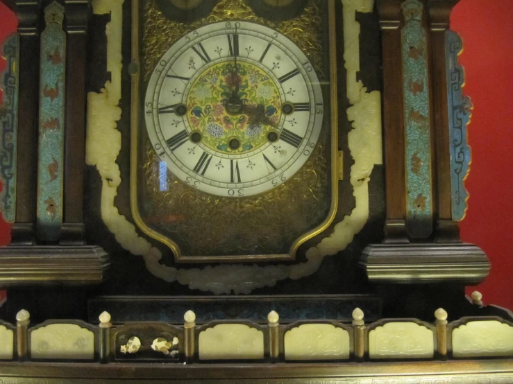 a clock with decorative wooden details on red wall