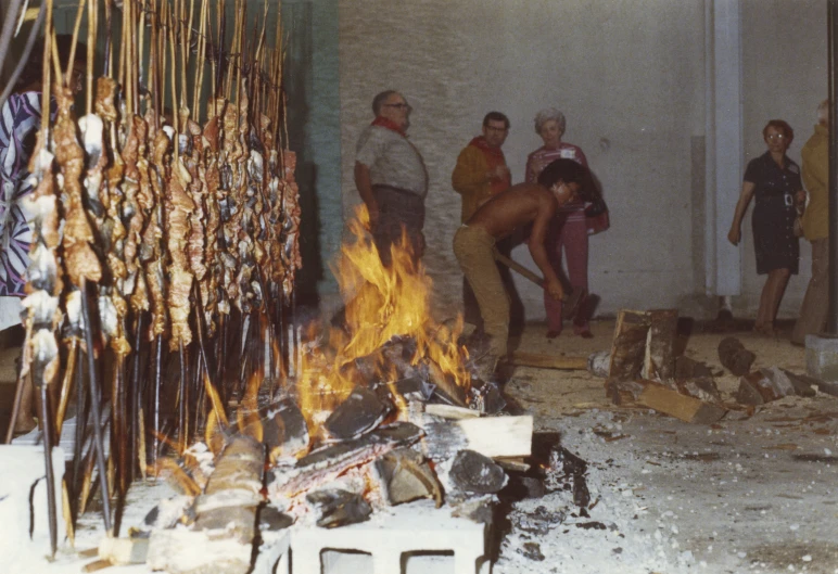several people standing around fire burning sticks