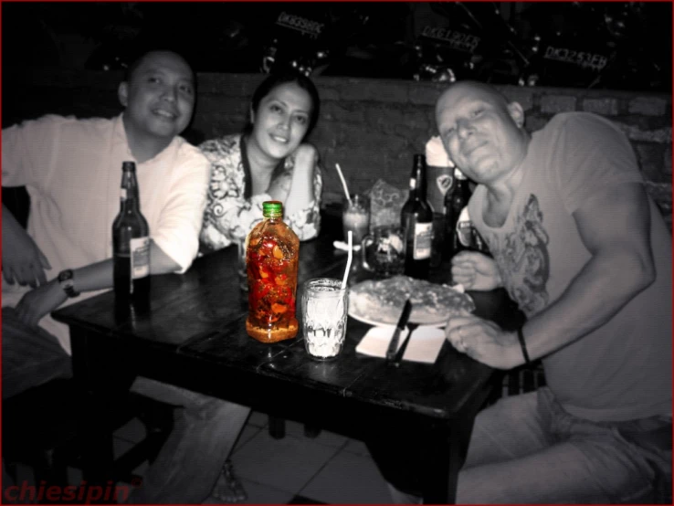 three friends are posing for the camera at a table with drinks