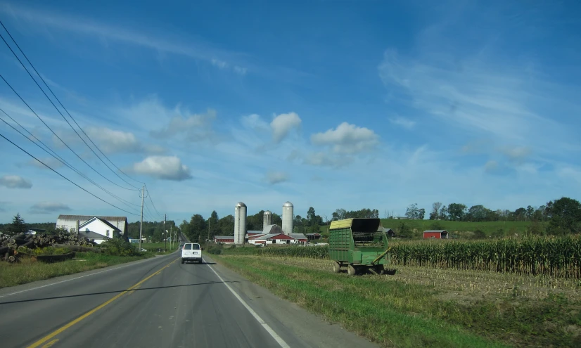 a truck driving down a street past some grass