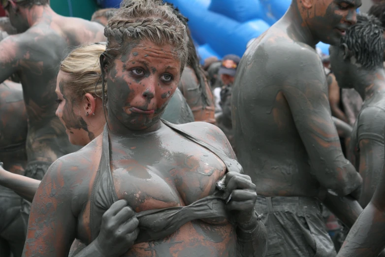 a couple of women covered in mud with people covered in mud