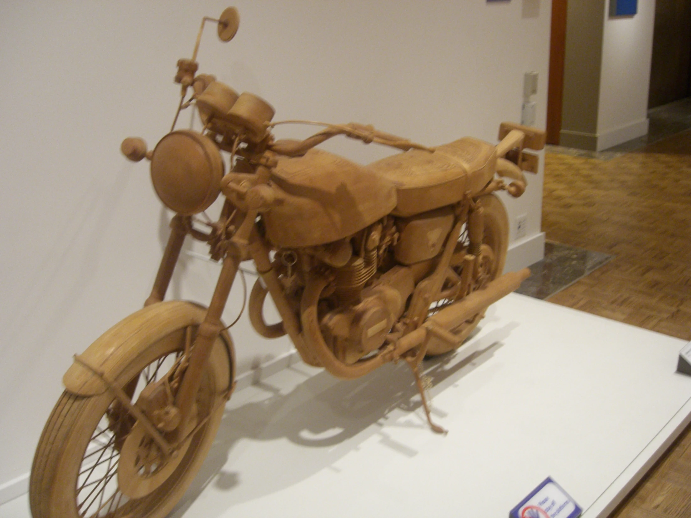 wooden motorcycle is sitting on display in a museum