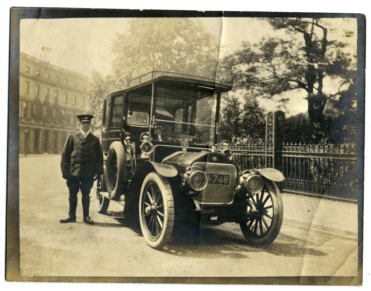 a very old po showing people standing in front of an old time car