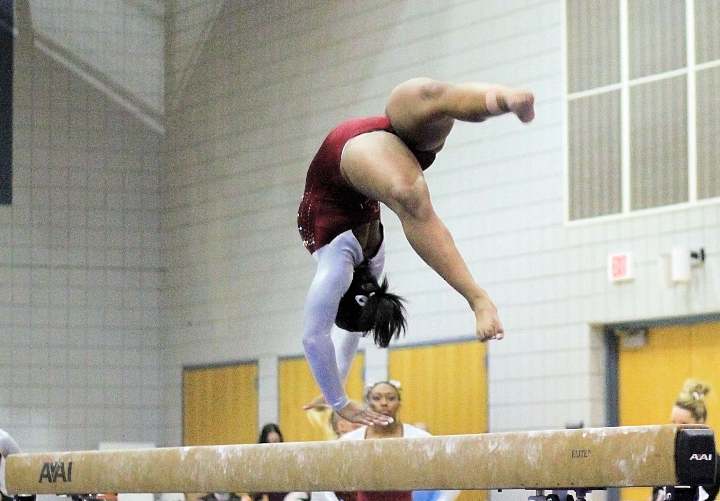 a girl does a handstand on a balance beam