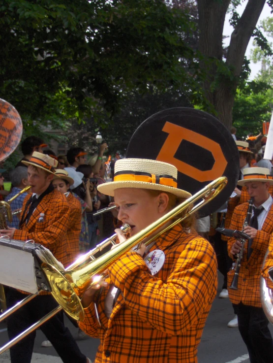 several children in orange and black clothes playing trombones