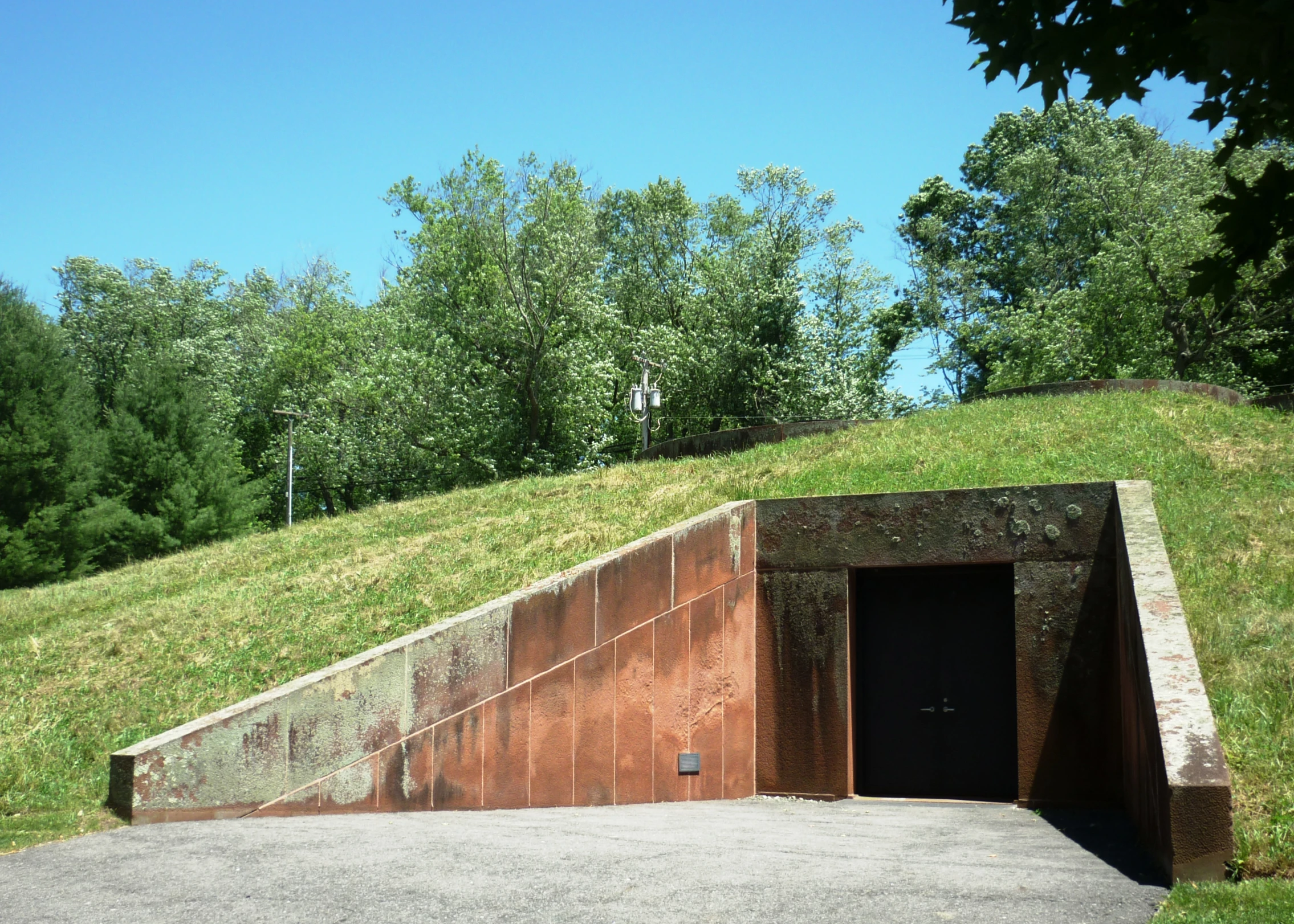 a concrete ramp in front of a field and trees