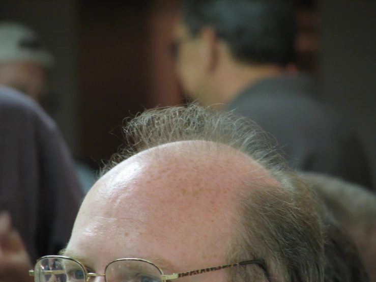 a close up view of a bald man with glasses