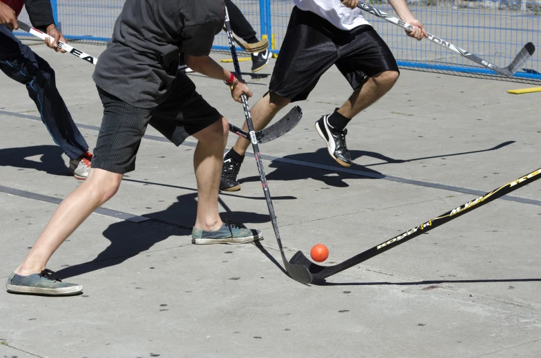 four people playing hockey on a court with red balls