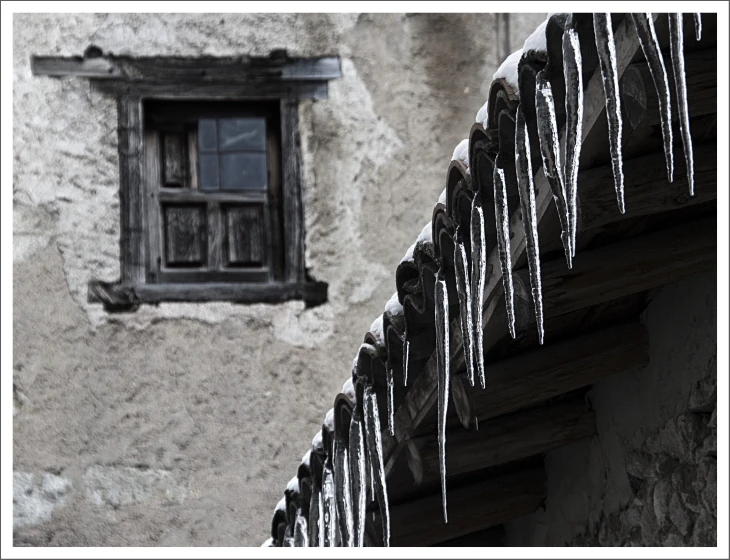 icicles are hanging on a railing near a window