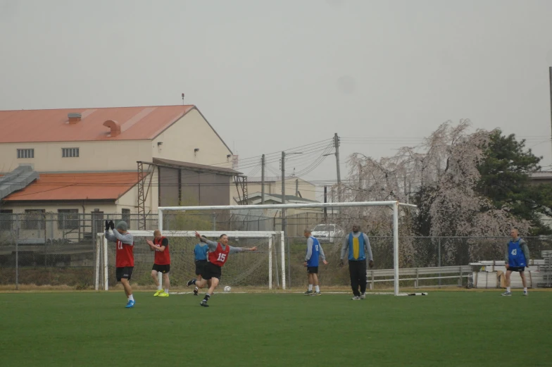 several soccer players play a game with a fence around them