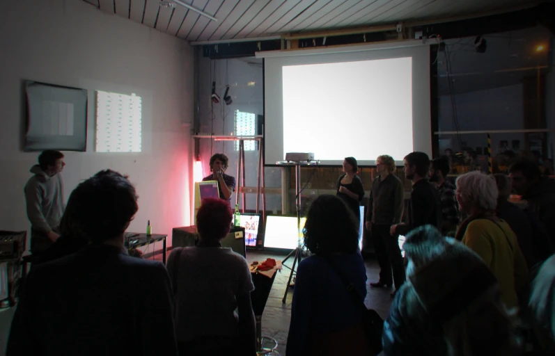 a group of people standing around in front of a projector