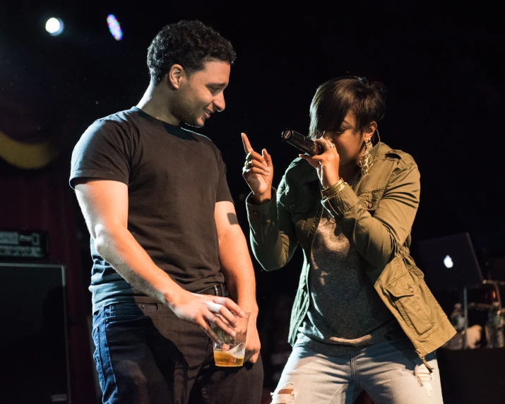 a man standing next to a woman in front of a microphone