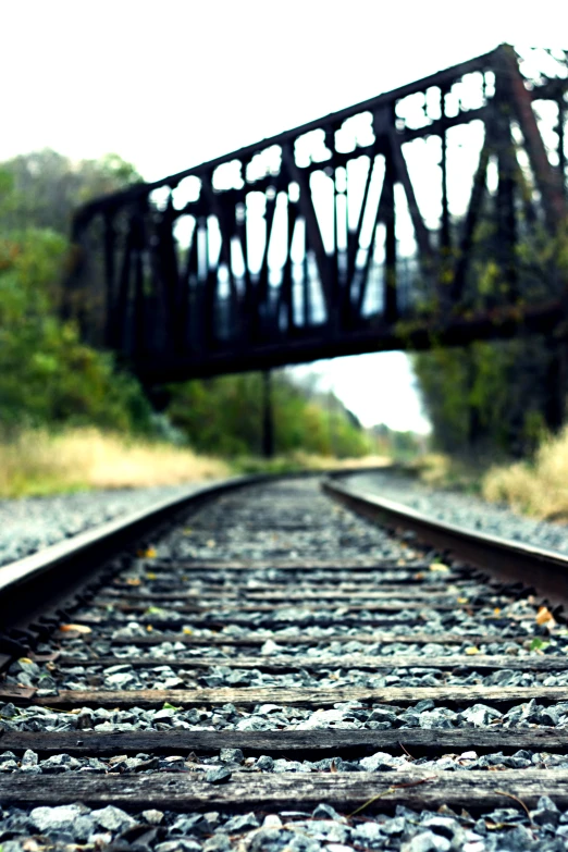 a railroad track with some rusty iron bridges above