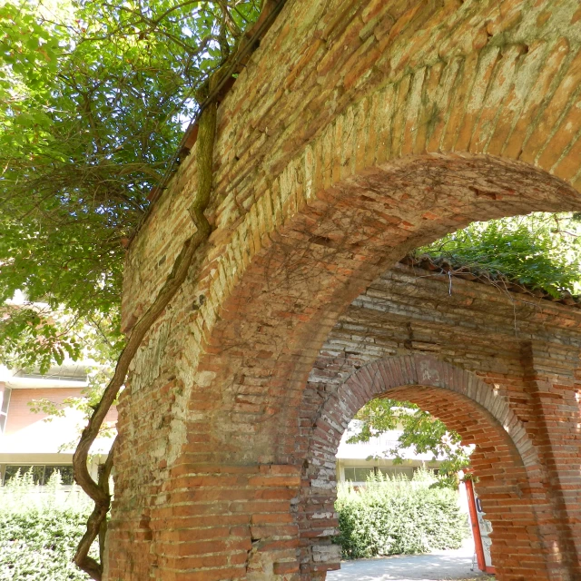 a clock is seen through an arch that shows it is brick