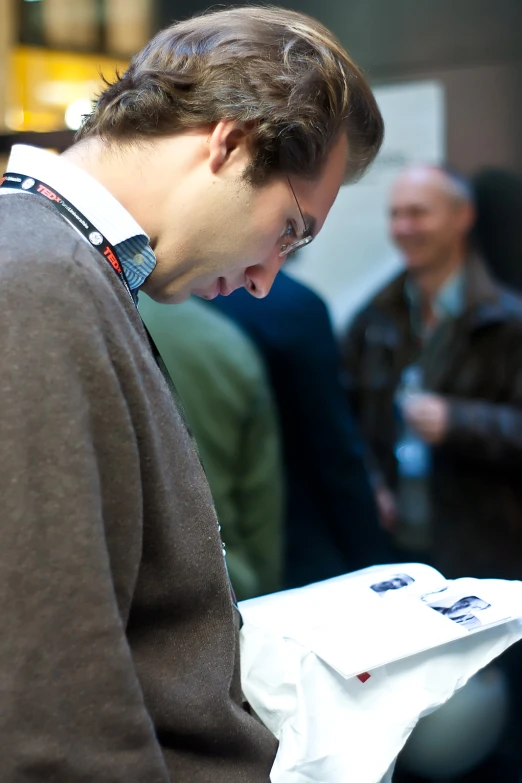 a young man in a sweater holding a piece of paper