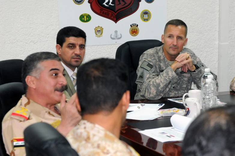 a man talking to a group of military men sitting around a table