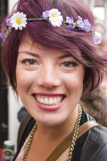 a woman with purple hair is wearing flowers in her head