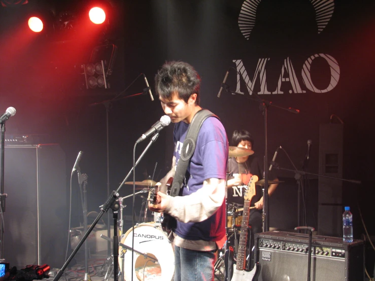 a man with a guitar playing in front of a microphone and microphone mic