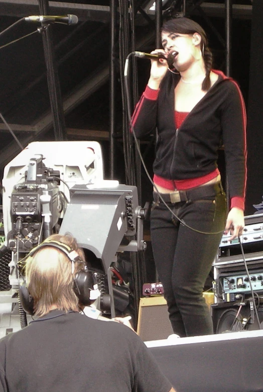 a woman in red shirt and headphones sings on stage